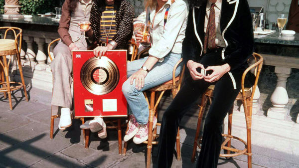 Queen: John Deacon (v.l.), Freddie Mercury, Roger Taylor und Brian May 1976 mit einer Platin-Platte. Foto: picture alliance/dpa