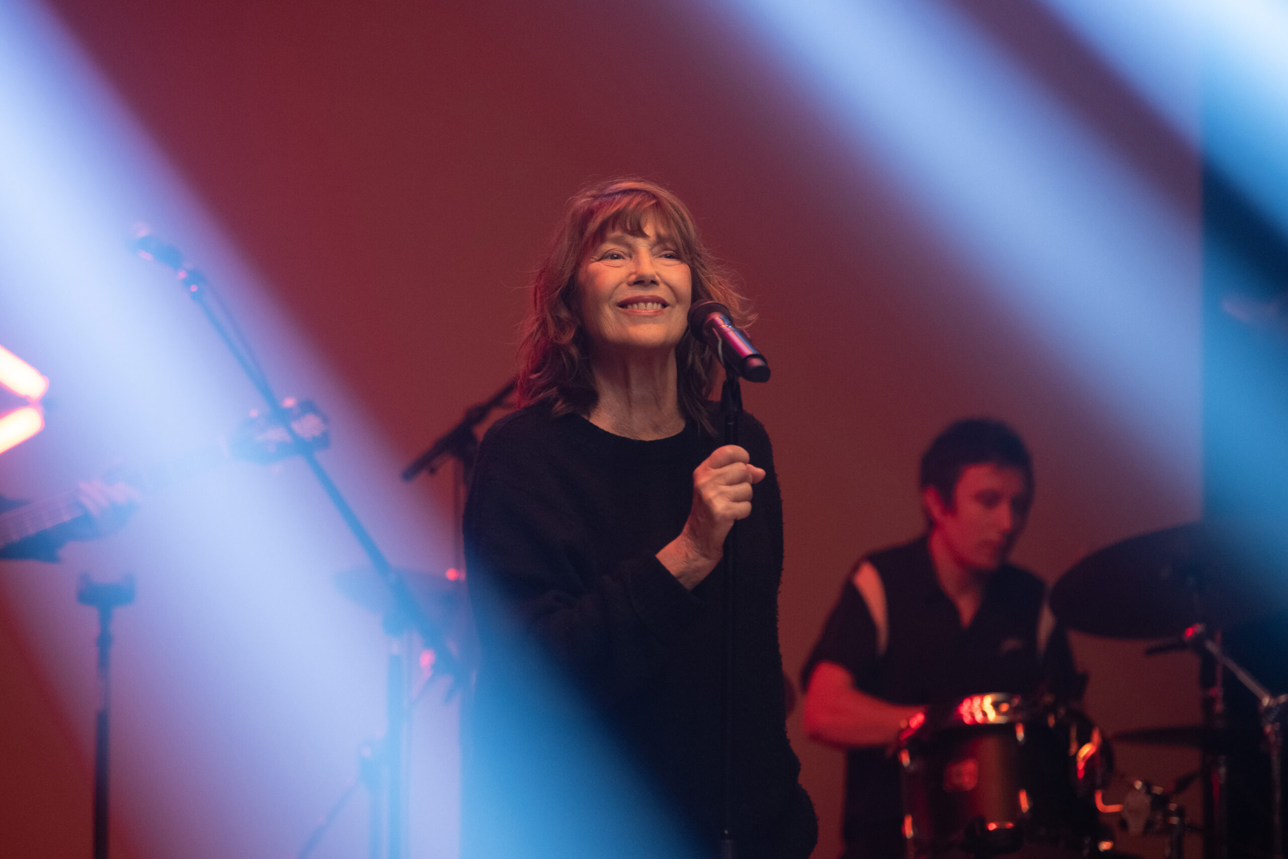 Jane Birkin auf der Bühne vorm Mikrofon, im Hintergrund ein Schlagzeuger