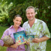 Sänger Sasha und seine Frau Julia Röntgen stehen mit dem Kinderbuch und Album „Toto und der Mann im Mond“ im Garten ihres Grundstücks.