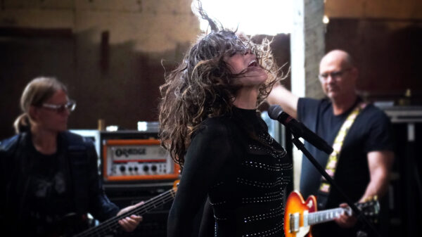 Hart vorne wirbelt ihre Haare durch die Gegend, im Hintergrund Bassist und Gitarrist