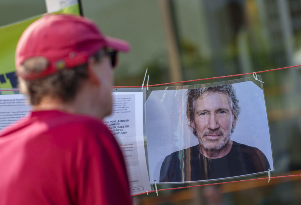Ein Mann betrachtet das Porträt von des Musiker Roger Waters bei einer Gegenveranstaltung.