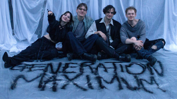 Die Sängerin und die Musiker sitzen auf dem Boden, auf den mit schwarzer Farbe "Generation Maximum" gesprüht wurde.