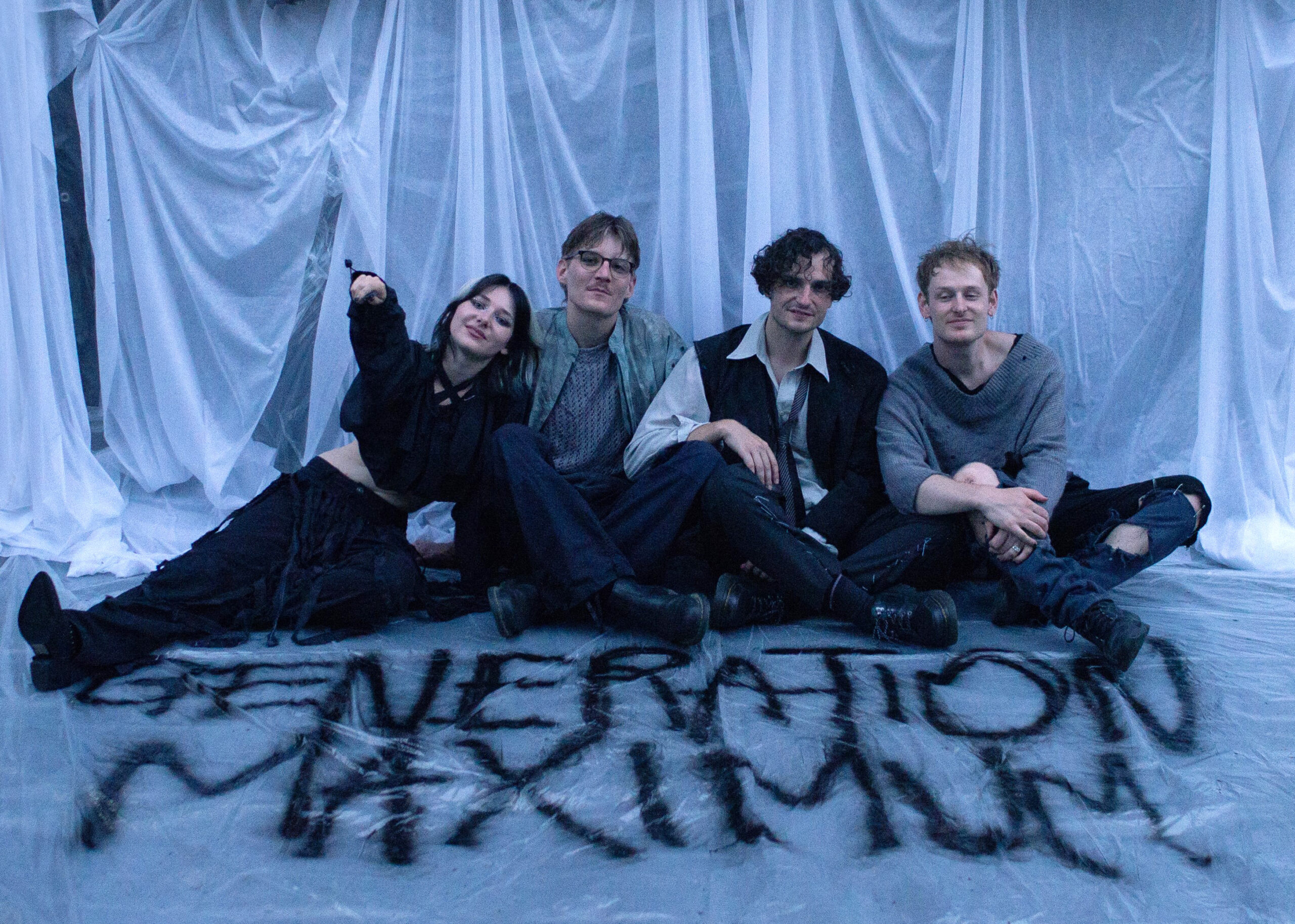 Die Sängerin und die Musiker sitzen auf dem Boden, auf den mit schwarzer Farbe "Generation Maximum" gesprüht wurde.