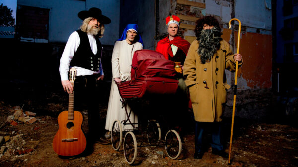 Die Band verkleidet mit Instrumenten und Kinderwagen vor einem Abrisshaus