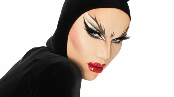 Sasha Velour trägt ein schwarzes Kostüm mit spitzen "Ohren" und ist unter anderem mit roten Lippen und auffälligem Augen-Make-up geschminkt