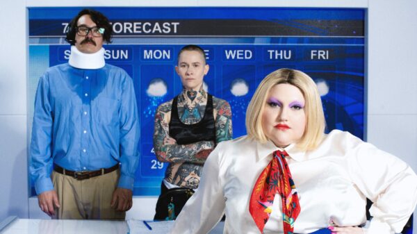 Drei Menschen in einer Art TV-Studio, im Hintergrund eine Wettervorhersage