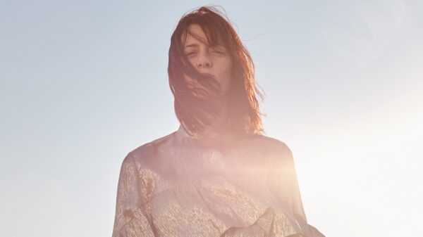 Steht vor blauem Himmel, die Haare ein bisschen verweht