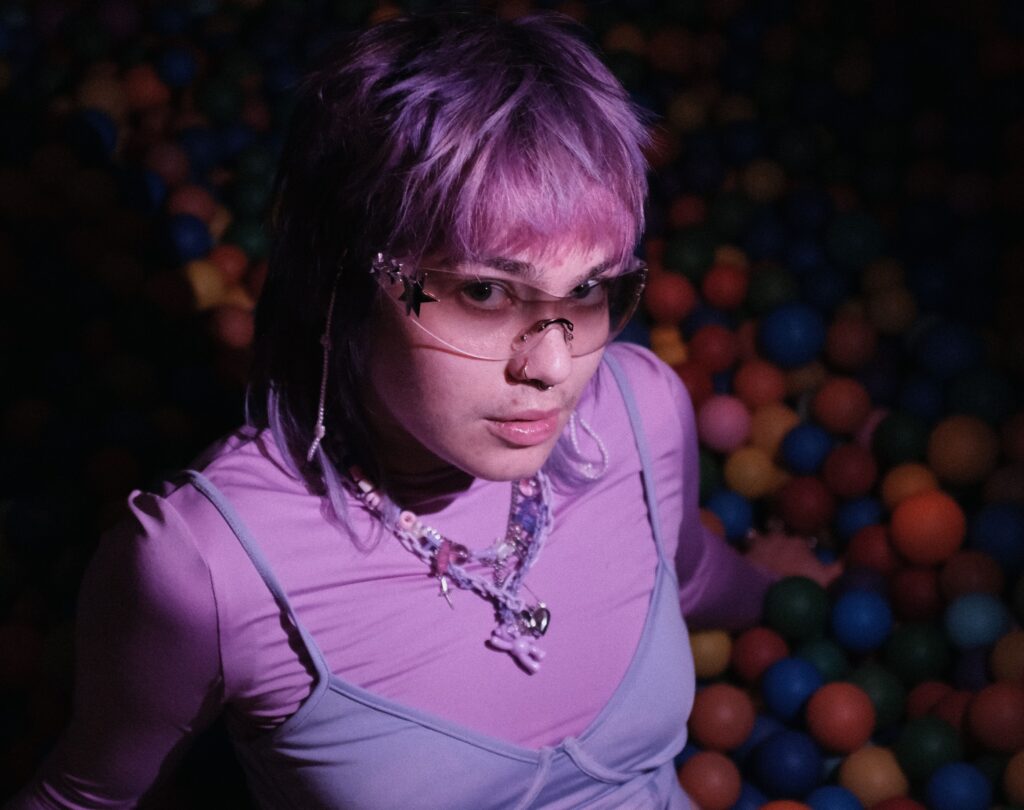 Lila Haare, lila Sonnenbrille, lila Klamotten: Lila Sovia sitzt auf dem Boden