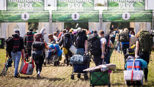 Menschen mit Rucksäcken ziehen und tragen ihr Gepäck über einen abgemähten Acker