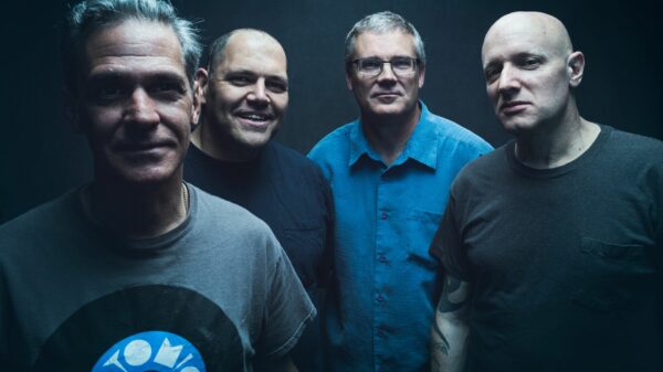 Vier Männer vor schwarzem HIntergrund, alle lächeln