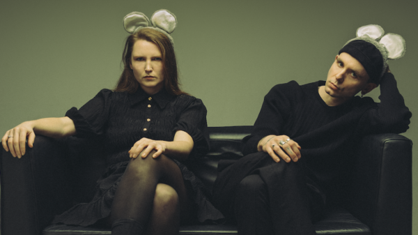 Beide sitzen auf einem Sofa und haben Haarreifen mit Mäuseohren auf dem Kopf