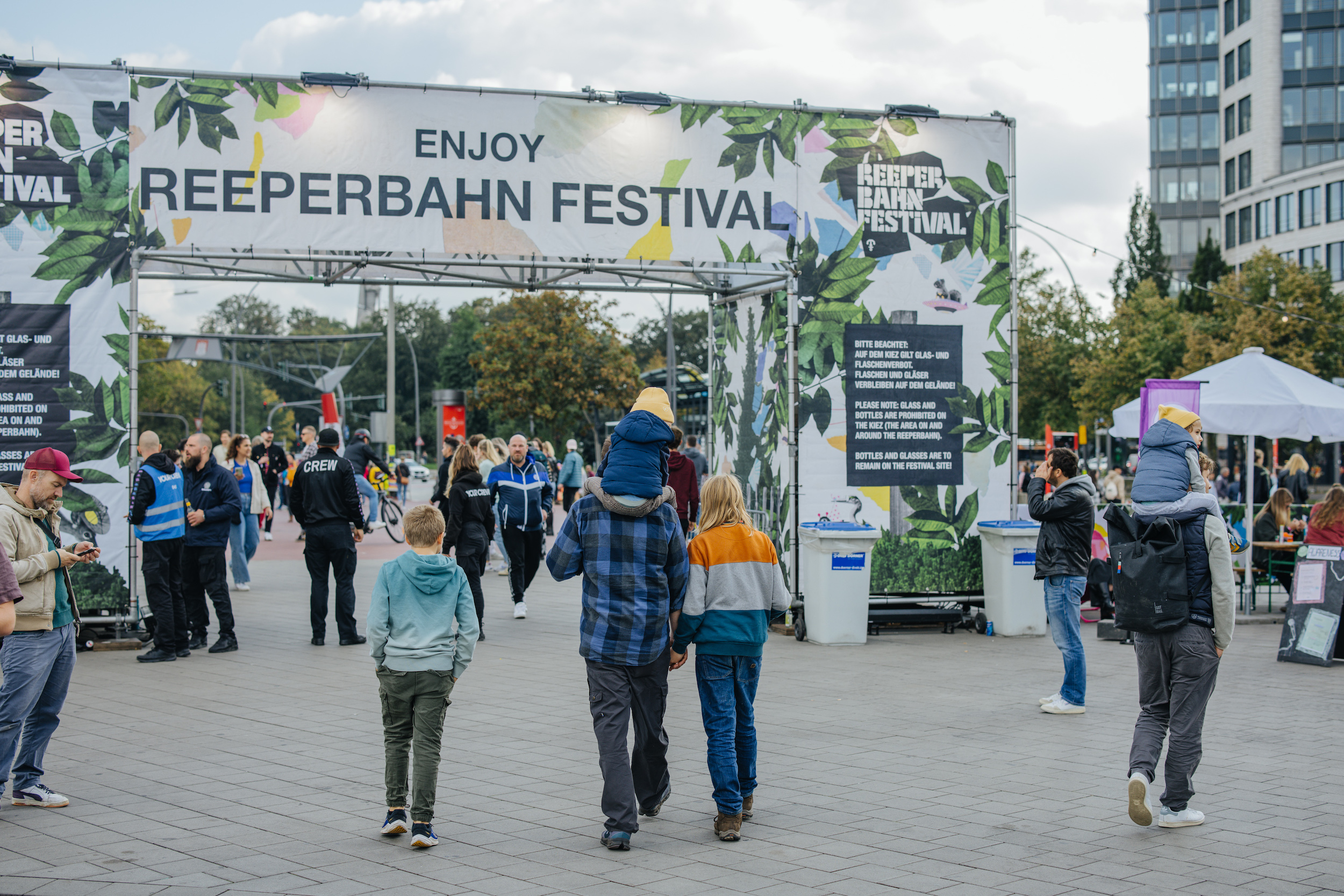 Blick aufs Heiligengeistfeld, Menschen laufen unter einem Torbogen durch, auf dem „Enjoy Reeperbahn-Festival“ steht.