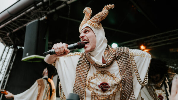 Band auf der Bühne, der Sänger trägt ein Kostüm mit vielen Ketten und Nieten und Hörner auf dem Kopf aus Ketten und Nieten