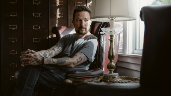 Frank Turner sitzt auf einem Sessel, vor ihm eine Lampe. Er schaut schräg aus dem Fenster