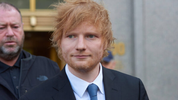 Ein Mann mit roten Haaren und Bart (Ed Sheeran) im Anzug