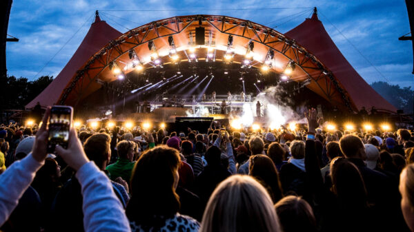 Besucher des „Roskilde“-Festivals feiern vor einer Bühne.