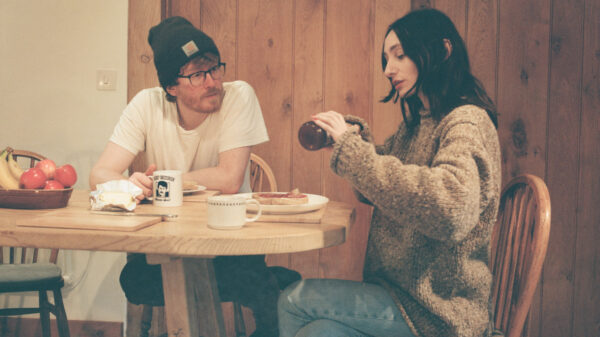 Ein Mann und eine Frau an einem Esstisch, er hält eine Tasse, sie kratzt etwas aus einem Glas