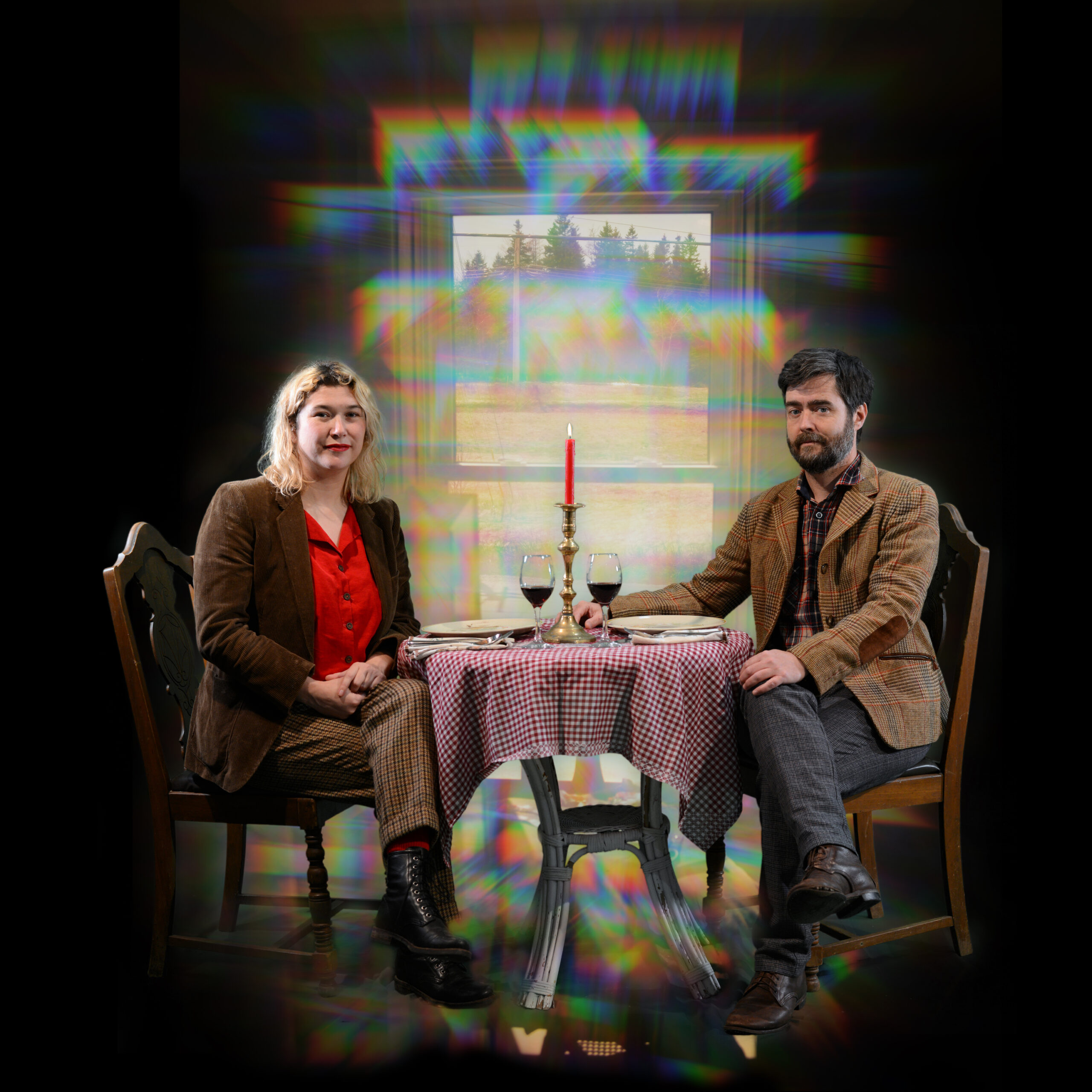 Eine Frau und ein Mann sitzen an einem Tisch mit Teller, Weingläsern und einem Kerzenständer