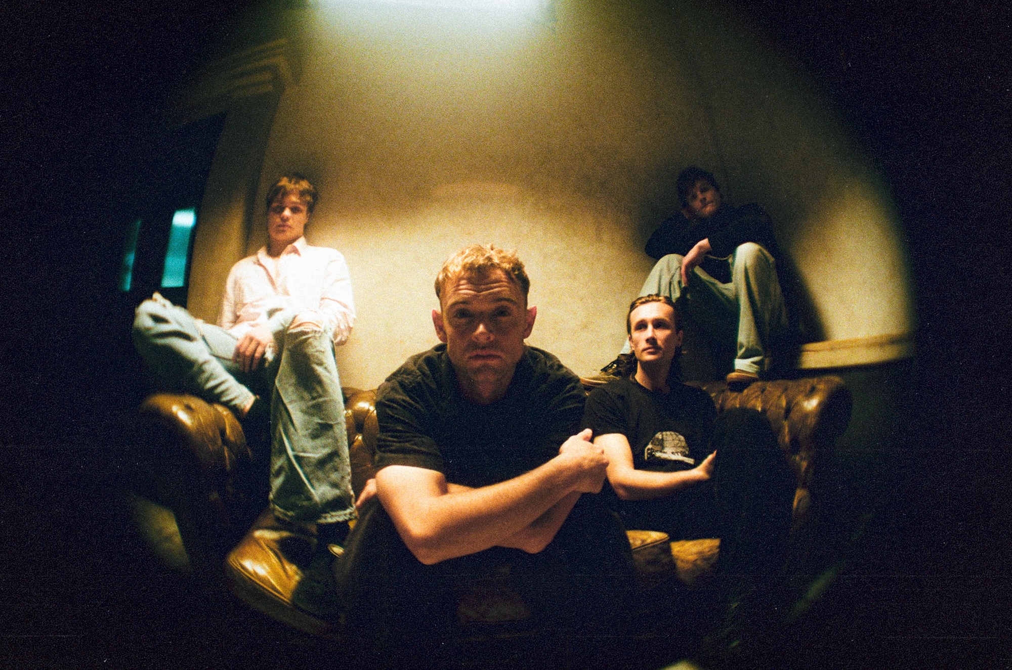 Die vier Männer sitzen auf und an einem brauen Ledersofa