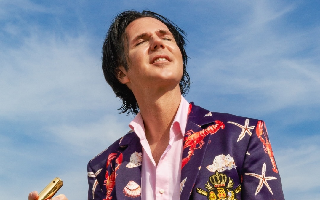 Alexander Marcus, dunkle Haare, er trägt ein bunt gemustertes Jackett.