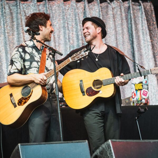 Beide mit Gitarren, sie lachen und umarmen sich