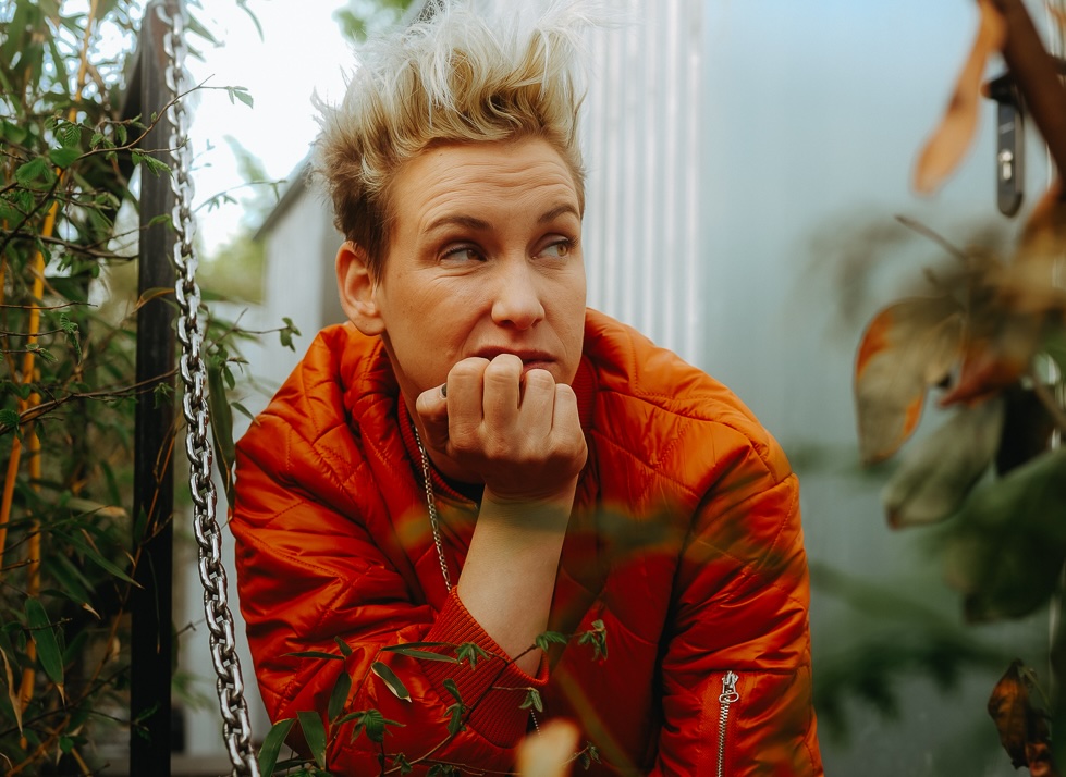 Sie sitzt zwischen Grün und einer Wand und guckt skeptisch zur Seite