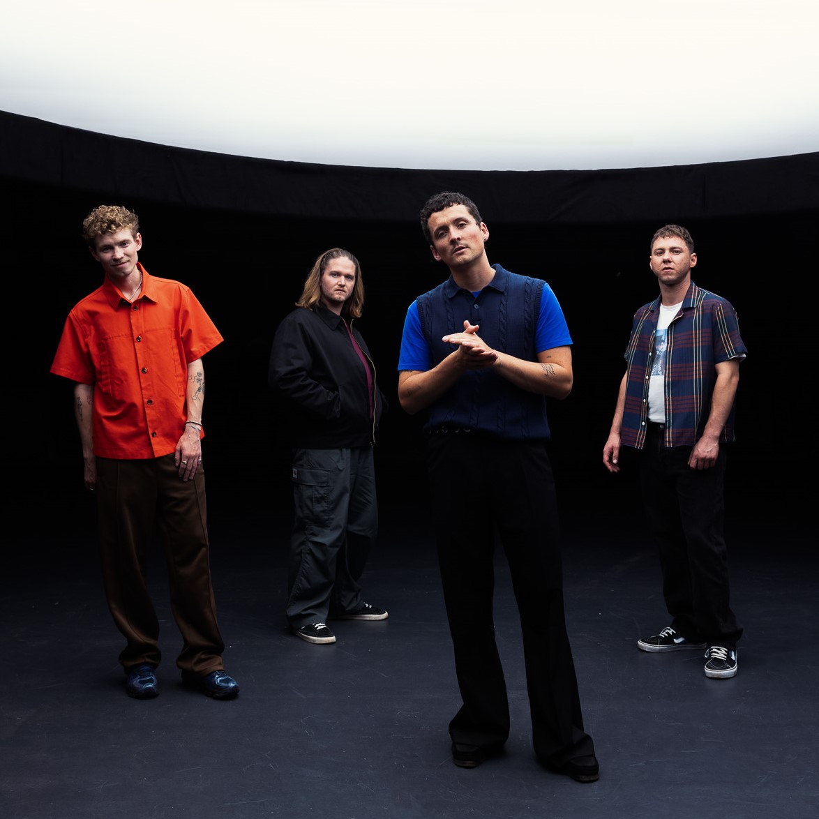 Vier Männer stehen vor einem schwarzen Hintergrund und schauen in die Kamera