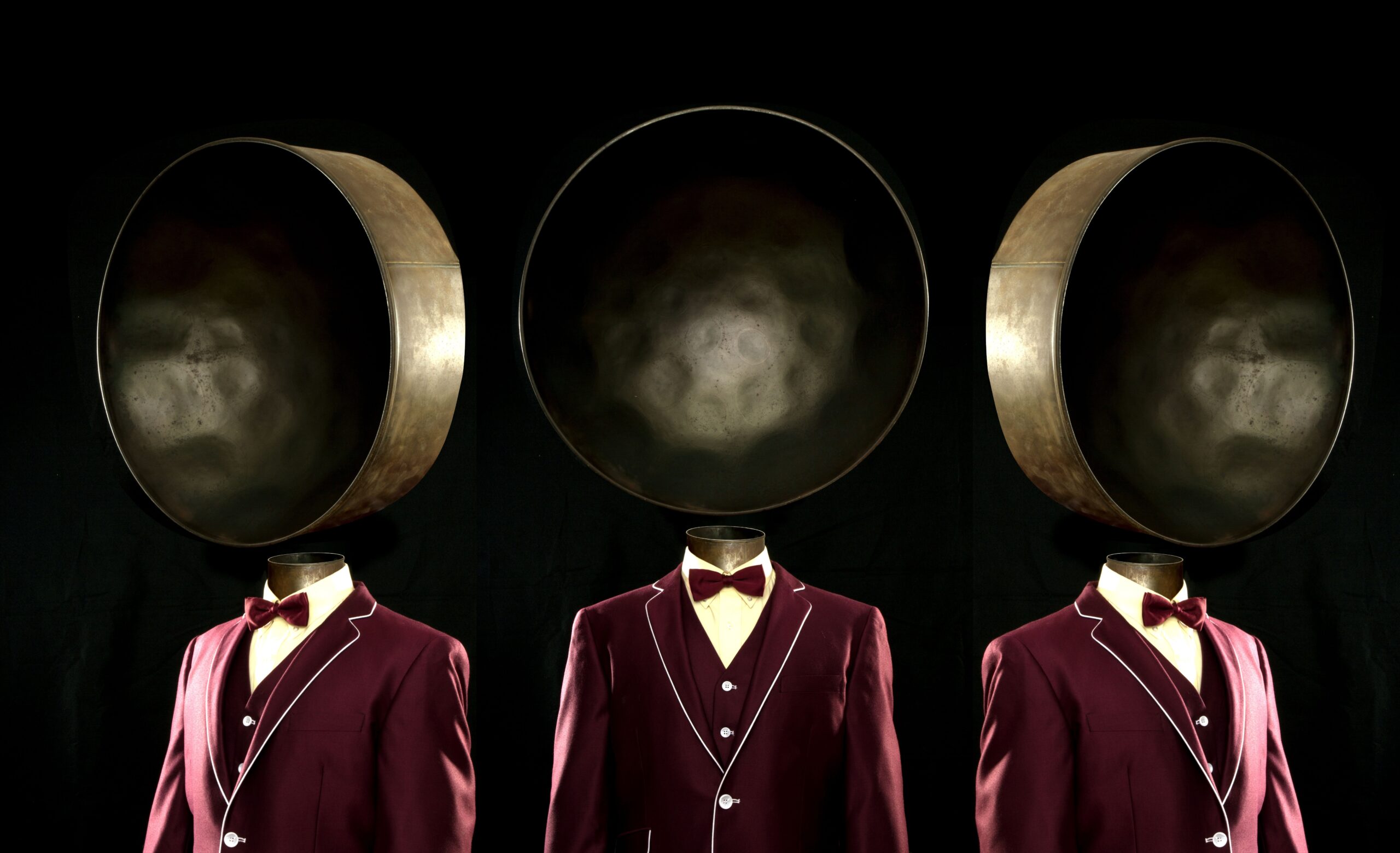 Drei „Personen“ in roten Anzügen, anstelle eines Kopfes haben sie je eine Steeldrum