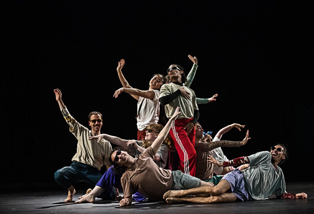 Mehrere Personen bei einer Performance, manche auf dem Boden liegend