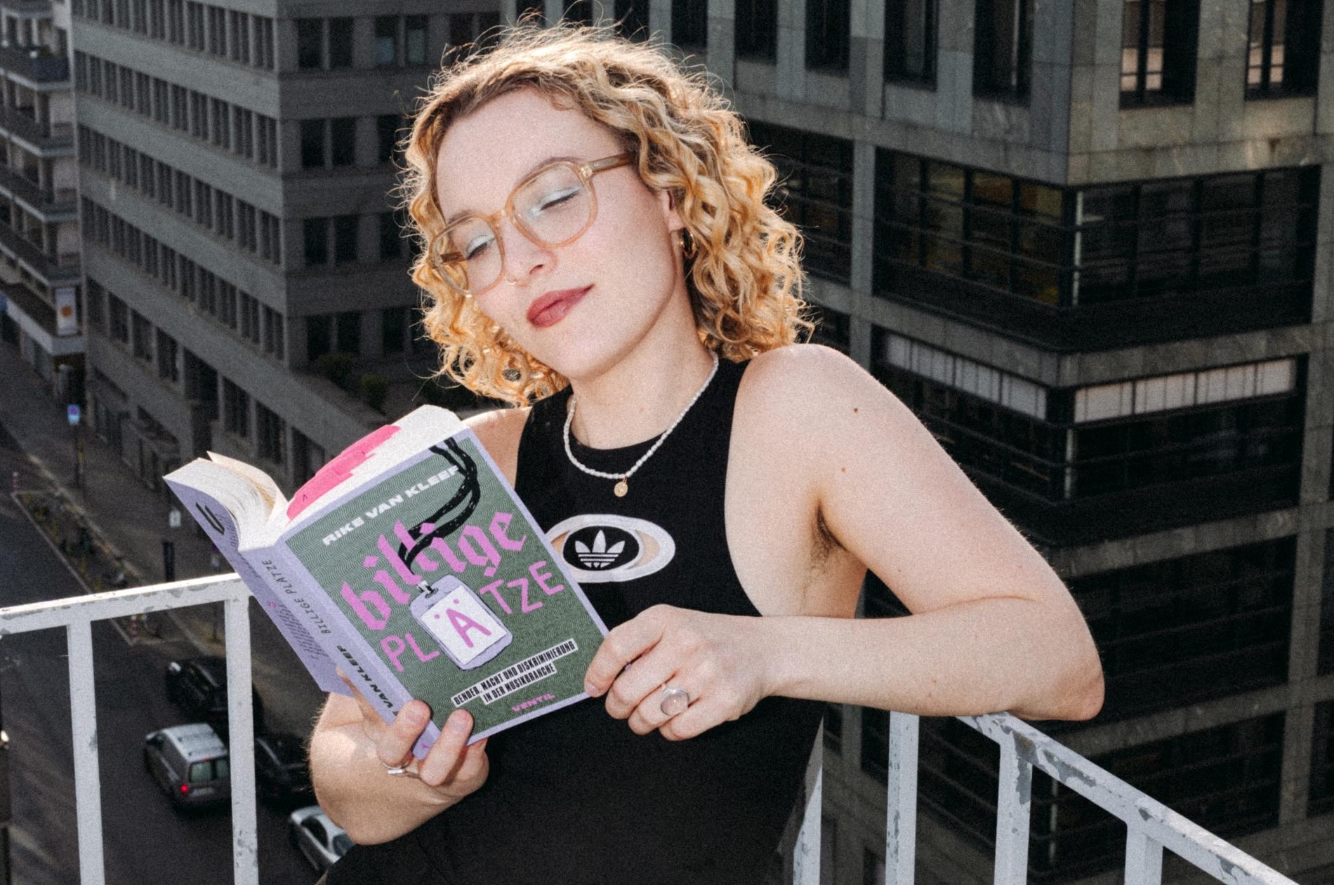 Sie steht auf einem Balkon, hat das Buch in der Hand und liest