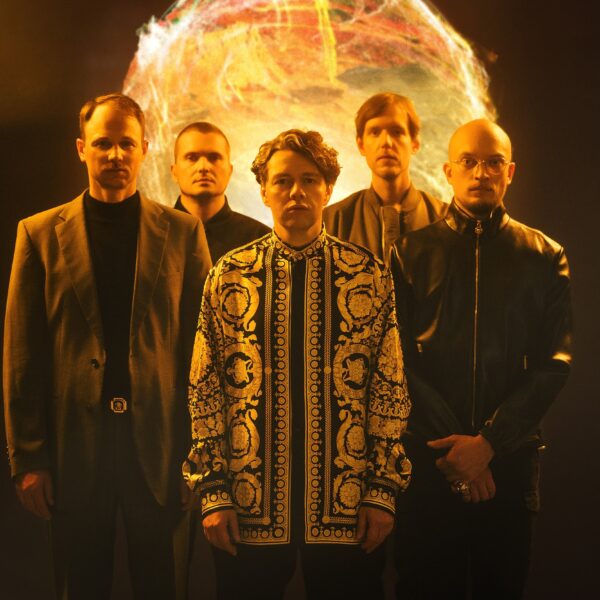 Fünf Männer stehen vor einer im Hintergrund angedeuteten Feuerkugel, vier tragen schwarze Kleidung, in der Mitte steht Christian Friedel in einem gemusterten Oberteil.