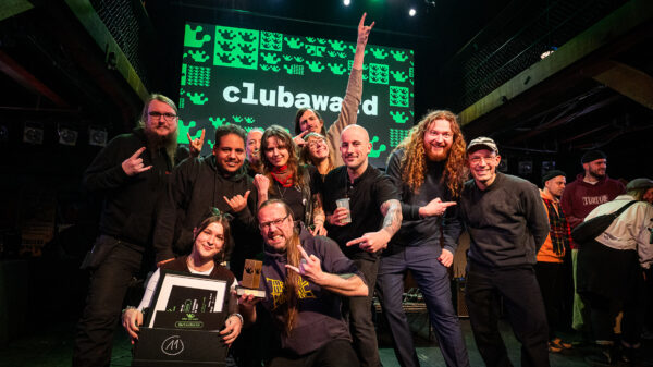 Viele lächelnde und lachende Menschen auf der Bühne, im Hintergrund steht auf einer Leinwand Clubaward