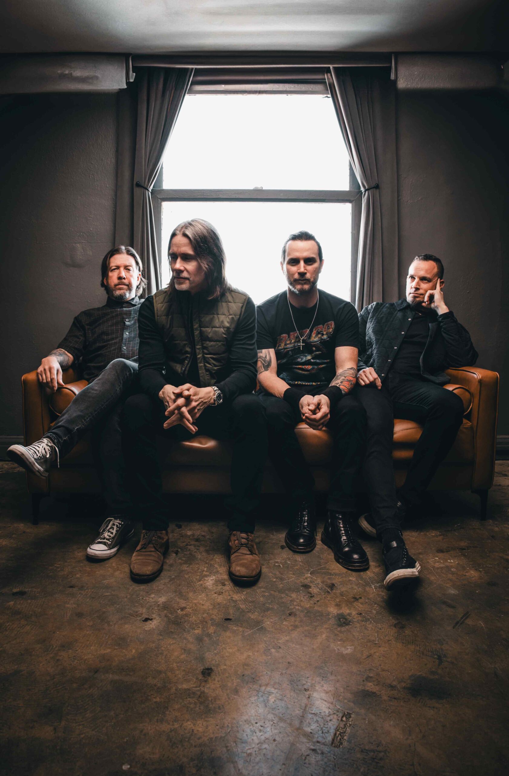 Die vier Mitglieder von Alter Bridge sitzen nebeneinander auf einem Sofa.