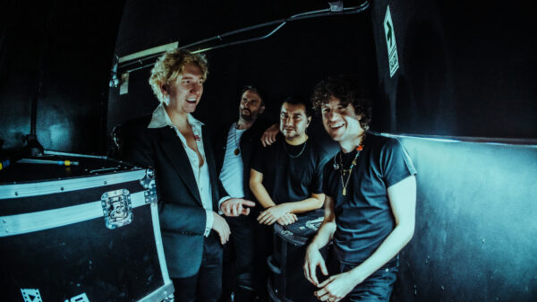 Dunkles Setting, vier Männer stehen nah beieinander, zwei von ihnen lachen, darunter auch Sänger Luke Pritchard, der rechts steht