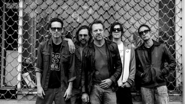 Fünf Männer stehen vor einem Schaufenster, vor dem ein Gitter runtergelassen ist. Bis auf Tom Barman tragen alle eine Sonnenbrille.