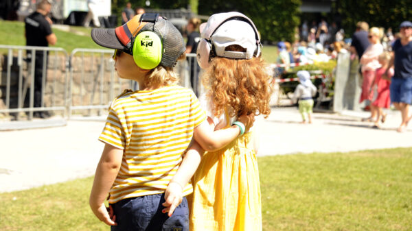 Zwei Kinder mit Kopfhörern stehen vor der Freilichtbühne im Stadtpark Hamburg beim Kinderkonzert.