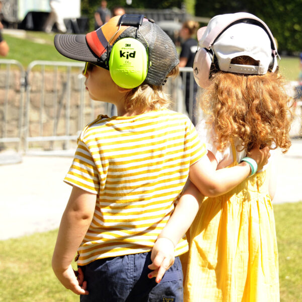 Zwei Kinder mit Kopfhörern stehen vor der Freilichtbühne im Stadtpark Hamburg beim Kinderkonzert.