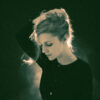 Agnes Obel steht im Gegenlicht auf der Bühne und blickt nach unten.
