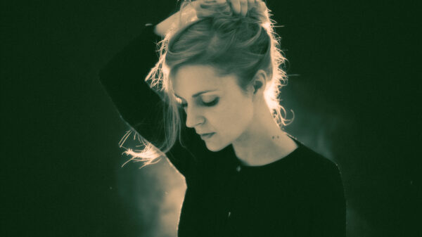 Agnes Obel steht im Gegenlicht auf der Bühne und blickt nach unten.