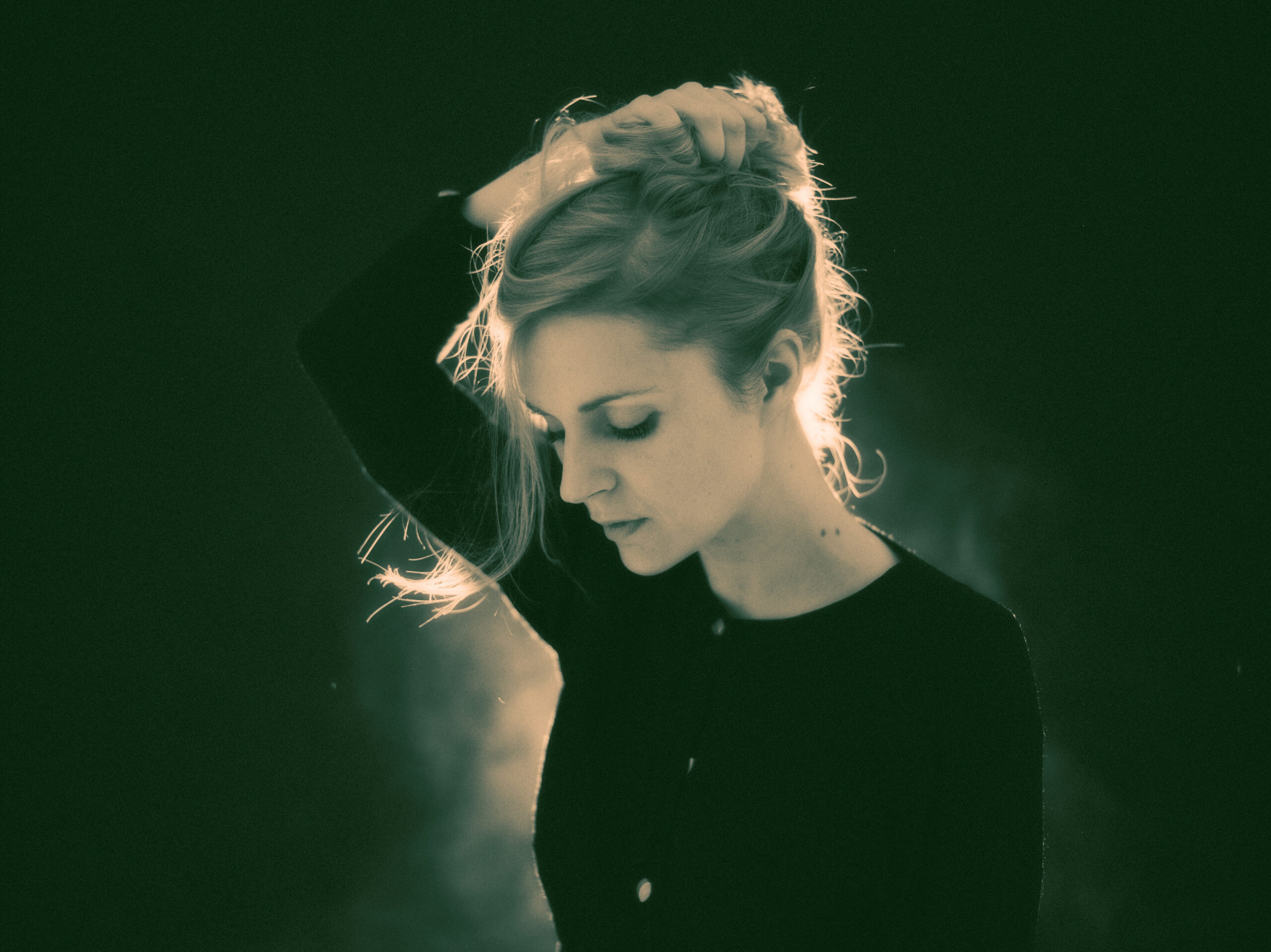 Agnes Obel steht im Gegenlicht auf der Bühne und blickt nach unten.